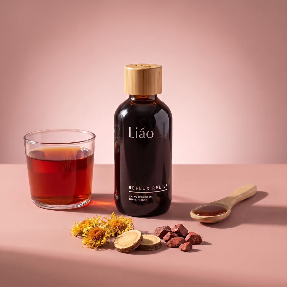 Liáo Reflux Relief bottle beside a glass of the syrup in warm water, a wooden spoon, inula flowers, licorice root and hematite