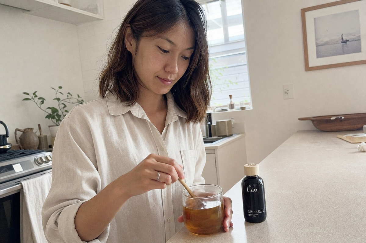 A woman stirring a spoon of Liao into warm water in her kitchen